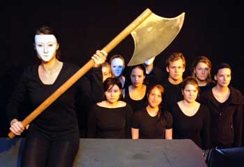 Das Foto zeigt in schwarz gekleidete junge Leute, eine junge Frau mit weißer Maske hält ein großes Beil in der Hand.