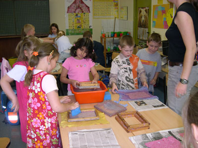 Das Foto zeigt viele Kinder an einem Tisch beim Papier schöpfen