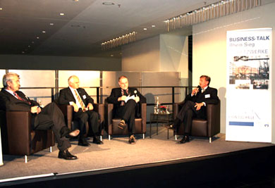 Das Foto zeigt vier Männer in schwarzen Ledersesseln beim Business-Talk auf der Bühne der Rhein-Sieg-Halle