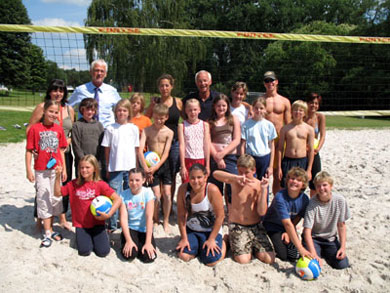 Das Foto zeigt die Kinder der Volleyballmannschaften sitzend und kniend im Sand, im Hintergrund Bürgermeister Franz Huhn