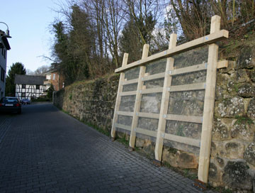 Eine Holzkonstruktion stützt die  Mauer in Wolsdorf 