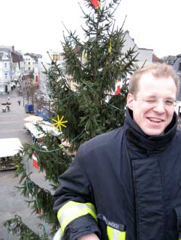 Ein Mitarbeiter der Feuerwehr vor einem geschmückten Weihnachtsbaum