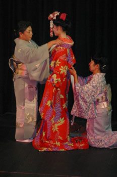 Drei Japanerinnen zeigen die Kunst des Bekleidens mit einem Kimono