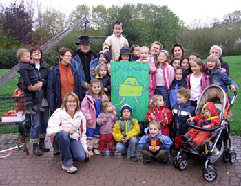 Das Bild zeigt Eltern und Kinder mit einem Spielmobil-Banner